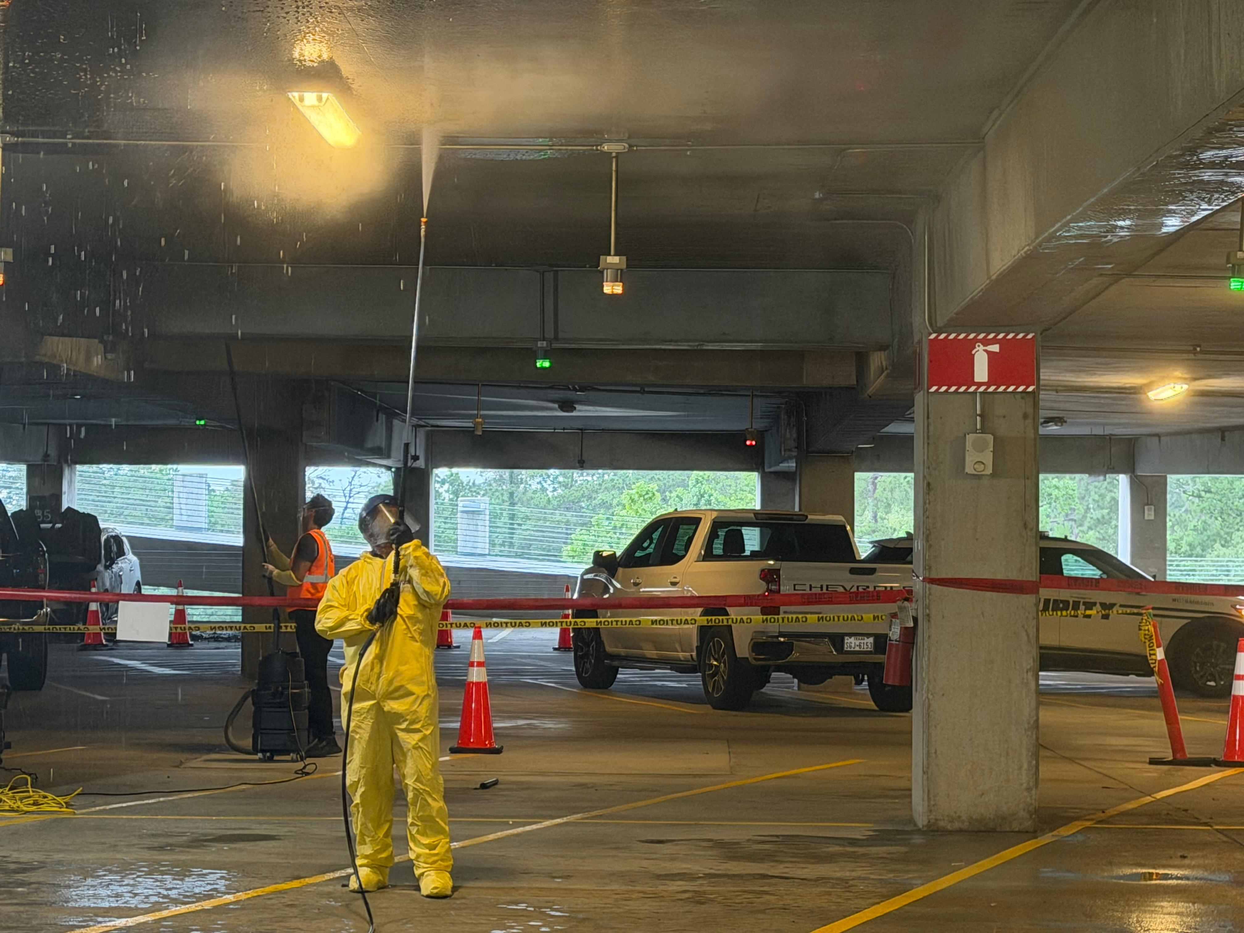 Technician pressure washing a parking garage ceiling